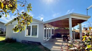 Low HeadLOW HEAD beachside bungalow "Cockle Shell"的白色房子上的木凉棚