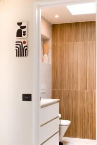 een badkamer met toilet en houten wand bij The Blue Tajinaste in Caleta De Fuste +20 foto's