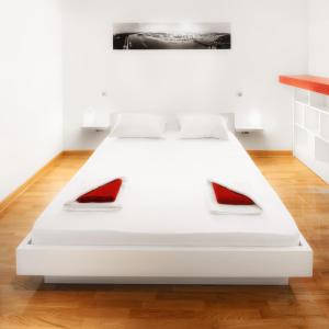 a white bed with red pillows on top of it at Downtown Belgrade Apartments - CHERRY in Belgrade