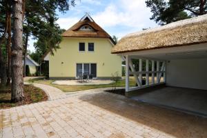 une maison avec un toit de chaume et un patio dans l'établissement -"Strandvilla - Vier Jahreszeiten" Doppelhaushälfte-, à Dierhagen