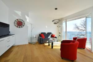 a living room with red chairs and a clock on the wall at Suite Meersinn in Sassnitz