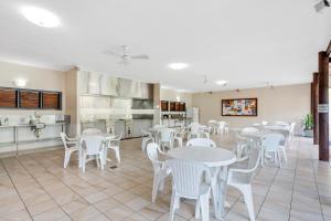 a dining room with white tables and white chairs at Cooktown Holiday Park in Cooktown