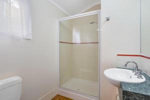 a bathroom with a shower and a toilet and a sink at Cooktown Holiday Park in Cooktown +16 photos