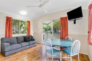 a living room with a couch and a table and chairs at Cooktown Holiday Park in Cooktown