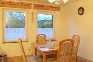 a dining room with a table and chairs and two windows at Kleiner Bungalow in Grömitz