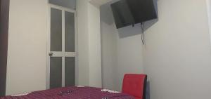 a room with a red chair and a tv on the wall at Hotel San Miguel in San Miguel