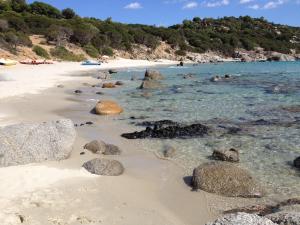 a sandy beach with rocks in the water at B&B Hibiscus in Capoterra