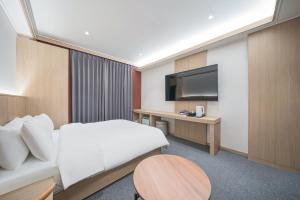 大邱Hound Hotel DaeGu的一间带床、书桌和电视的酒店房间