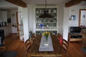 a dining room with a wooden table with flowers on it at Alte Mühle Schleiblick in Maasholm-Bad