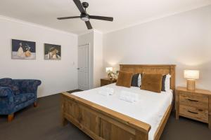 a bedroom with a large bed and a blue chair at Peppy Tree Bungalow in Dunsborough