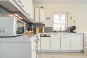 ツィングストにあるHuus Jetteの白いキャビネットと電子レンジを備えたキッチン