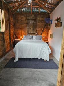 a bedroom with a white bed in a room with wooden walls at Cabañas en las Montañas in San Cristóbal