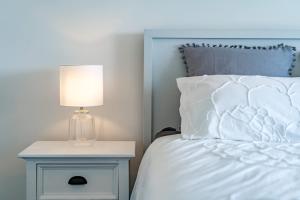 a white bed with a lamp on a night stand at 66 Neighbour Ave Goolwa - Linen Provided in Goolwa South