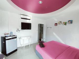 a bedroom with a pink bed and a kitchen at Thongtalay Bed & Breakfast Koh Larn in Ko Larn