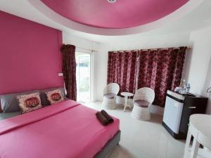 a bedroom with a pink bed and a table and chairs at Thongtalay Bed & Breakfast Koh Larn in Ko Larn