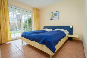 ein Schlafzimmer mit einem Bett mit einer blauen Decke und einem Fenster in der Unterkunft Birkenstraße 7 Whg 2 in Zingst