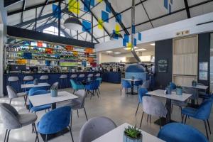 a restaurant with white tables and blue chairs at BellaMare in Port Elizabeth