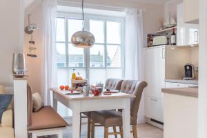 a kitchen with a white table and chairs and a table and a kitchen at Lütten Kate 03 in Zingst