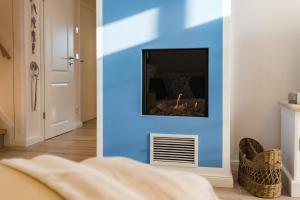 a living room with a blue wall with a fireplace at Lütten Kate 03 in Zingst