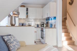 a small kitchen with white cabinets and a staircase at Lütten Kate 03 in Zingst +14 photos