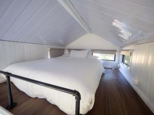 ein Schlafzimmer mit einem weißen Bett in einem Zimmer in der Unterkunft Baxter at Lake George Winery at Tiny Away in Collector