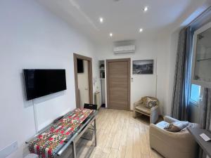 a living room with a table and a tv on a wall at Avaja - Daria's apartment in Taormina