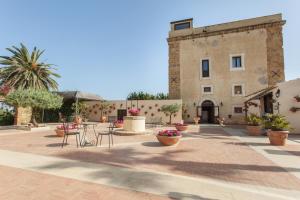 a courtyard with tables and chairs and a building at Hotel Foresteria Baglio Della Luna in San Leone