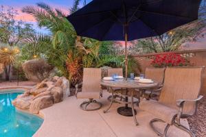a table and chairs with an umbrella next to a pool at Goodyear Springs in Goodyear