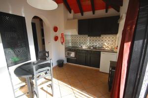 una cocina con armarios negros y una mesa. en Pedras D'el Rei Villa V1, en Tavira