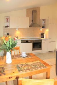 a kitchen with a wooden table with a vase of flowers at "Hof Triangel - Whg 1" - Bauernhofurlaub in Riepsdorf +11 photos