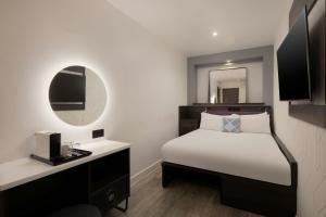 ロンドンにあるFour Points Flex by Sheraton London Shoreditch Eastのベッドと鏡のあるホテルの部屋