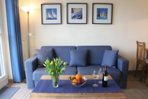 a living room with a blue couch and a table with a bowl of fruit at Ostseeresidenz - Whg 24 in Groß Kirr