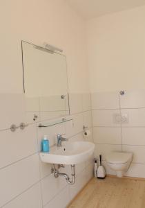 a white bathroom with a sink and a toilet at Haus Roy Ferienwohnung 1Etage in Zülpich