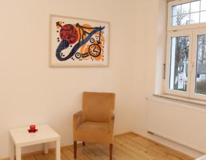 a room with a chair and a picture on the wall at Haus Roy Ferienwohnung 1Etage in Zülpich +3 photos