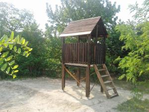 a wooden play tower with a ladder in a yard at Apartman Daniel in Balatonfőkajár