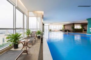 a large swimming pool in a building with windows at Lancaster Hanoi City Center Apartments in Hanoi