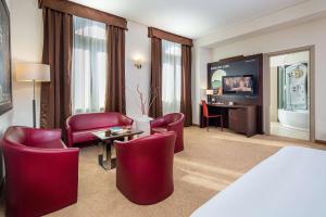 a hotel room with red chairs and a television at Europalace Hotel, BW Signature Collection in Monfalcone