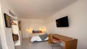 a bedroom with a bed and a desk and a television at Kiwidestiny Alicante in San Juan de Alicante
