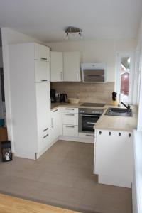 a white kitchen with white cabinets and a sink at FeHa Strandmügge in Zingst