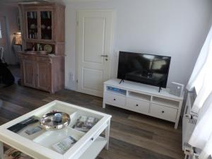 a living room with a television on a white entertainment center at Reetkehlchen in Alkersum