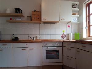 a kitchen with white cabinets and an oven at Ferienhäuschen Neuberend in Neuberend +12 photos