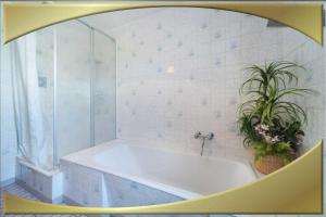 a white bathroom with a tub and a plant at Ferienwohnung in Waldidylle
