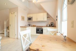 a kitchen with white cabinets and a wooden table at Ostseeidyll in Zingst