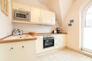 a kitchen with white cabinets and a sink and a microwave at Ostseeidyll in Zingst