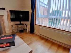 a living room with a large window and a television at Ipswich Town 3 Bed House in Copdock