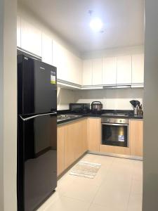 a kitchen with a black refrigerator and wooden cabinets at Opulent Spacious 3 BR Condominium at St Dominique at Megaworld in Iloilo City