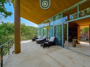 an outdoor patio with chairs and windows on a house at Luxury Oceanfront Villa - Private Pool -Temazacal in Chamela