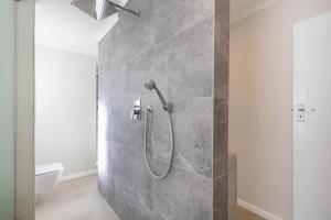 a shower in a bathroom with a stone wall at 4188 River Club in Plettenberg Bay +8 photos