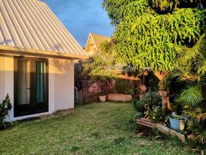 a yard with a house and a fence at Logement privé comprenant chambre, salle de bain, cuisine extérieure dans belle villa avec piscine vue ocean in La Possession