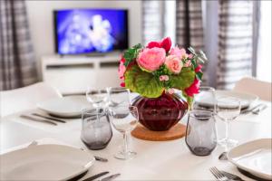 a table with a vase of pink flowers and glasses at Casaminnie - Appartement à 8 min de Disneyland Paris in Bussy-Saint-Georges